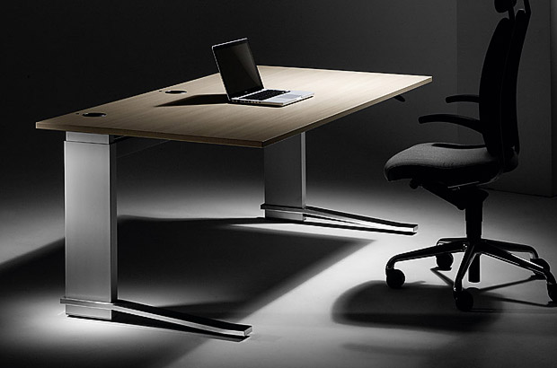 Ein großer, verstellbarer Schreibtisch mit schwarzem Bürostuhl davor