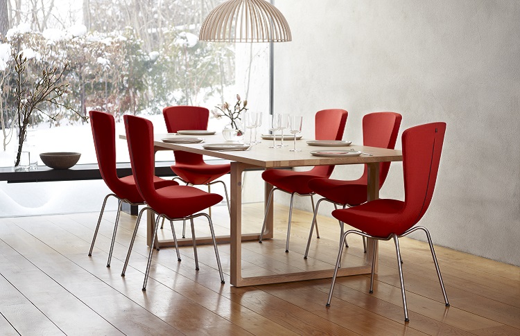 Sechs rote Stühle, die im Esszimmer um einen langen Holztisch stehen